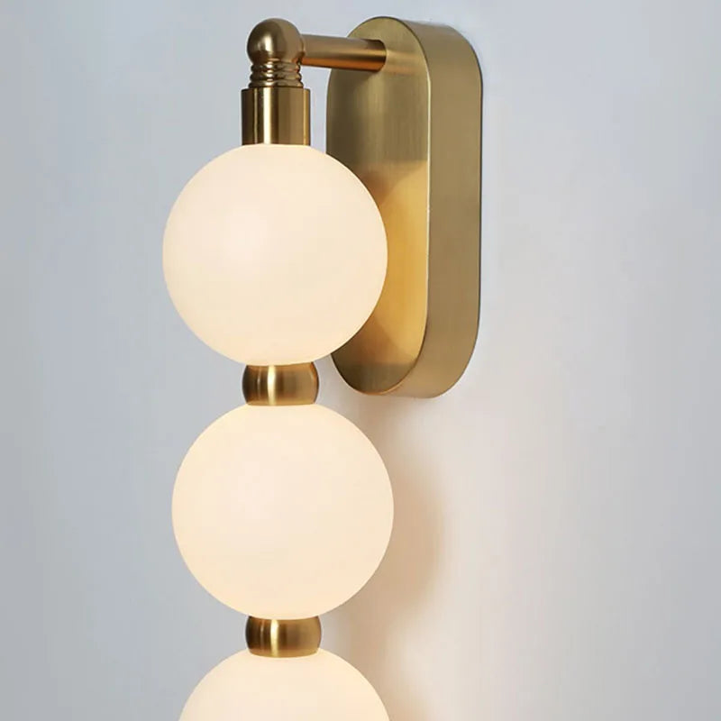 Vägglampa med tre akrylkulor och gyllene metallbas