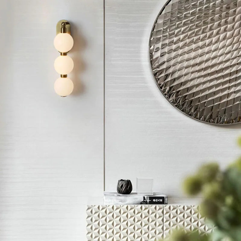 Vägglampa med tre akrylkulor och gyllene metallbas