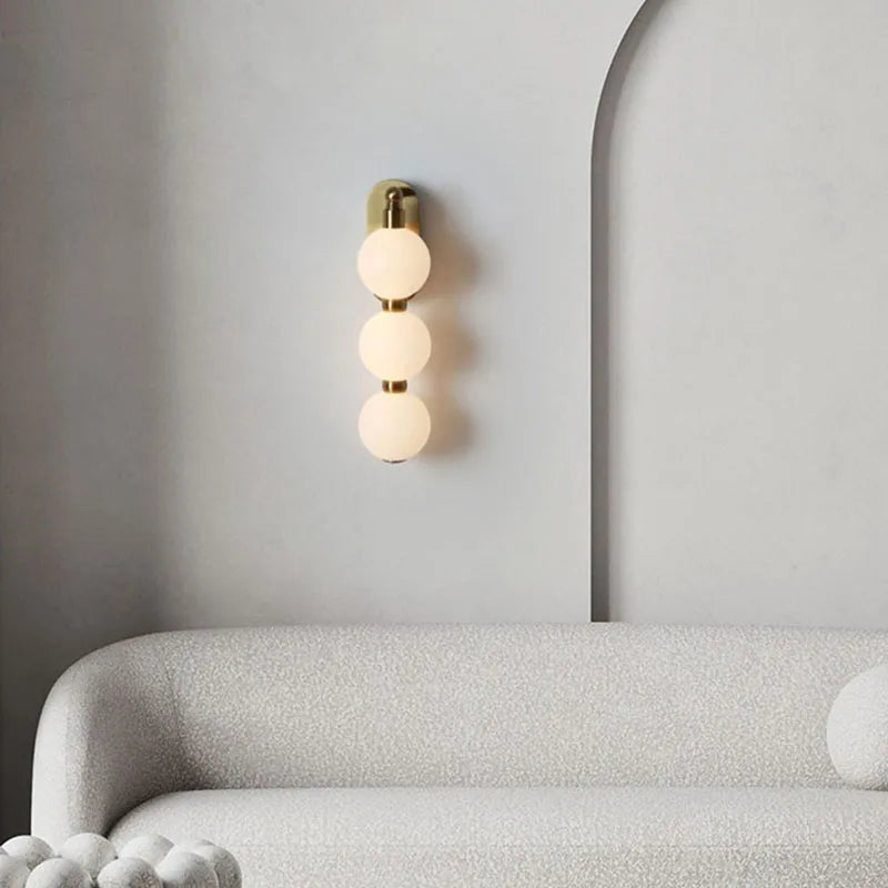 Vägglampa med tre akrylkulor och gyllene metallbas