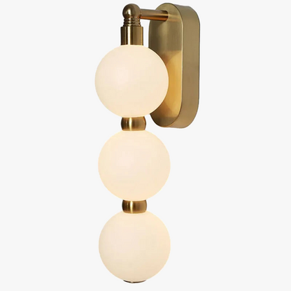 Vägglampa med tre akrylkulor och gyllene metallbas