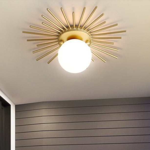 Taklampa i metall med solinspirerad design och glaskupa