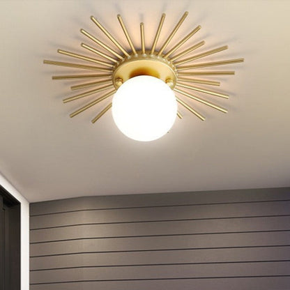 Taklampa i metall med solinspirerad design och glaskupa